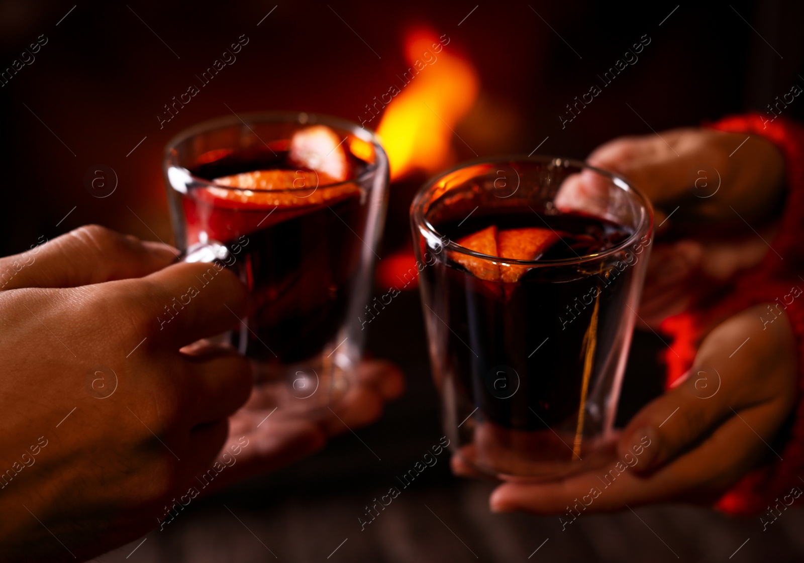 Photo of Couple with tasty mulled wine near fireplace indoors, closeup