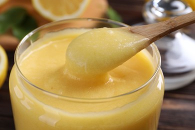 Taking delicious lemon curd from glass jar at table, closeup