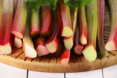 Photo of Many cut rhubarb stalks on white wooden table, closeup