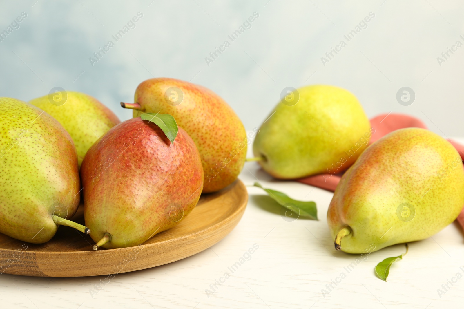 Photo of Ripe juicy pears on white wooden table against light background