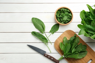 Photo of Fresh green sorrel leaves and knife on white wooden table, flat lay