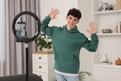 Photo of Smiling teenage blogger dancing while streaming at home