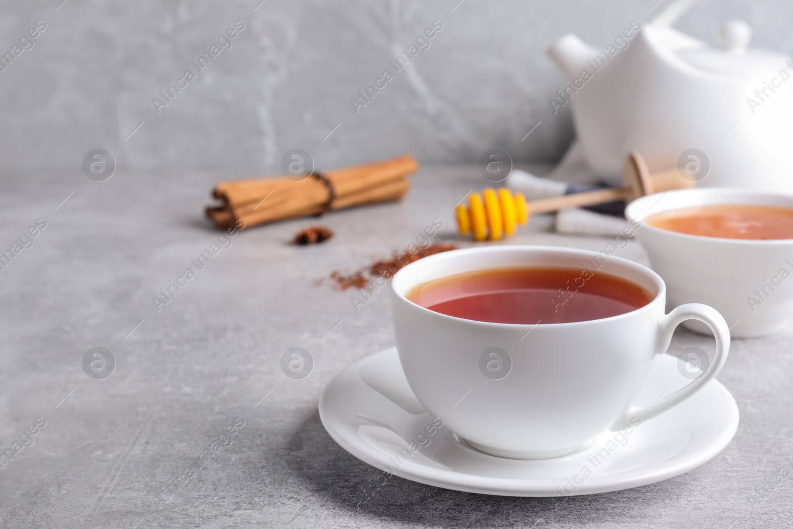 Photo of Freshly brewed rooibos tea on grey table. Space for text