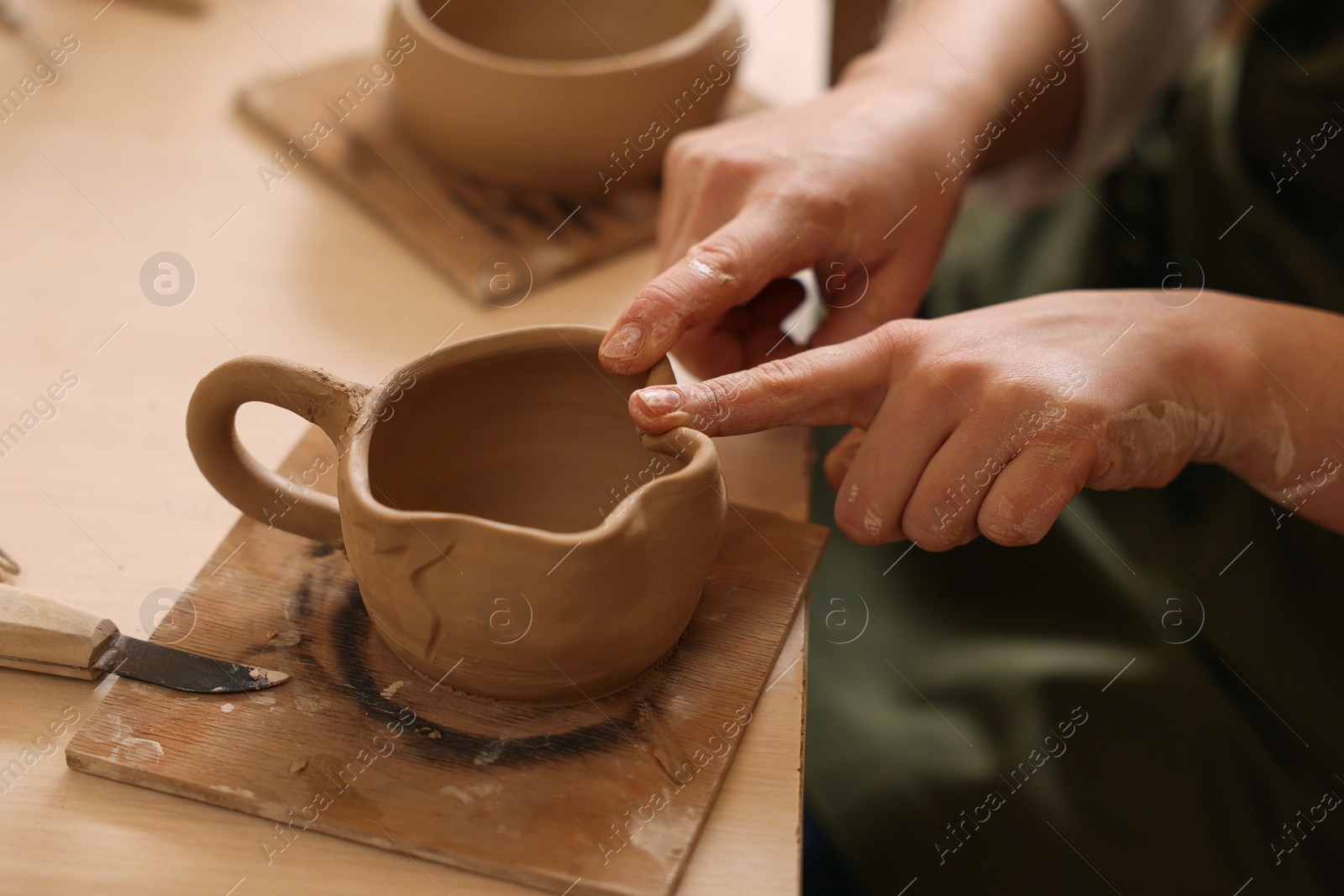 Photo of Pottery crafting. Woman sculpting with clay at table, closeup