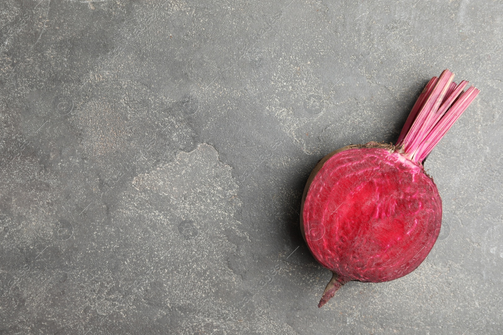 Photo of Half of raw beet on grey table, top view. Space for text