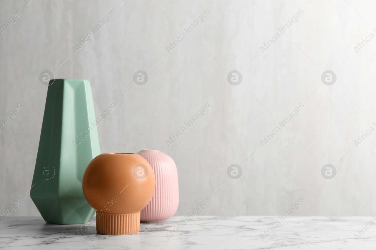 Photo of Stylish empty ceramic vases on white marble table, space for text