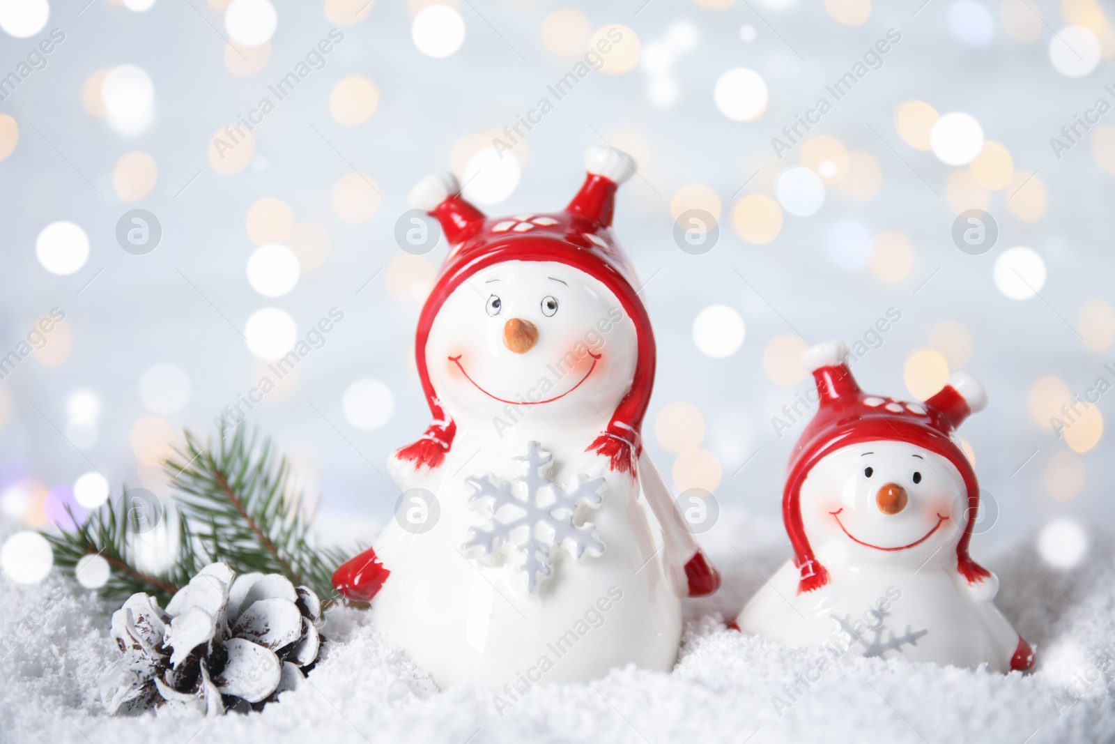 Photo of Christmas composition with decorative snowmen on artificial snow against blurred festive lights