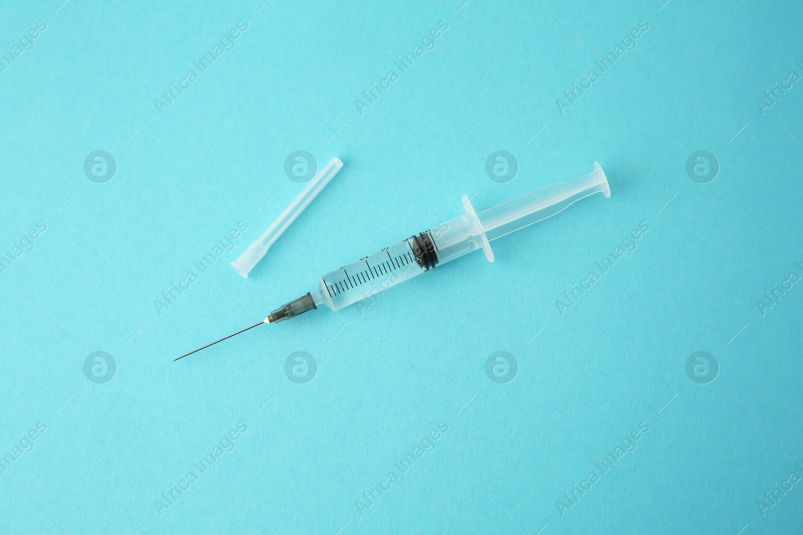 Photo of Medical syringe on light blue background, top view