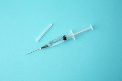 Photo of Medical syringe on light blue background, top view
