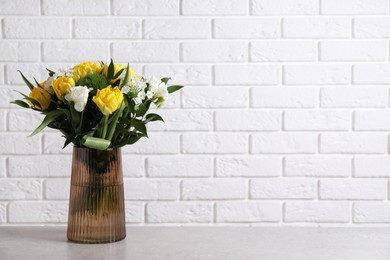 Photo of Beautiful bouquet with peony tulips on grey table near white brick wall. Space for text
