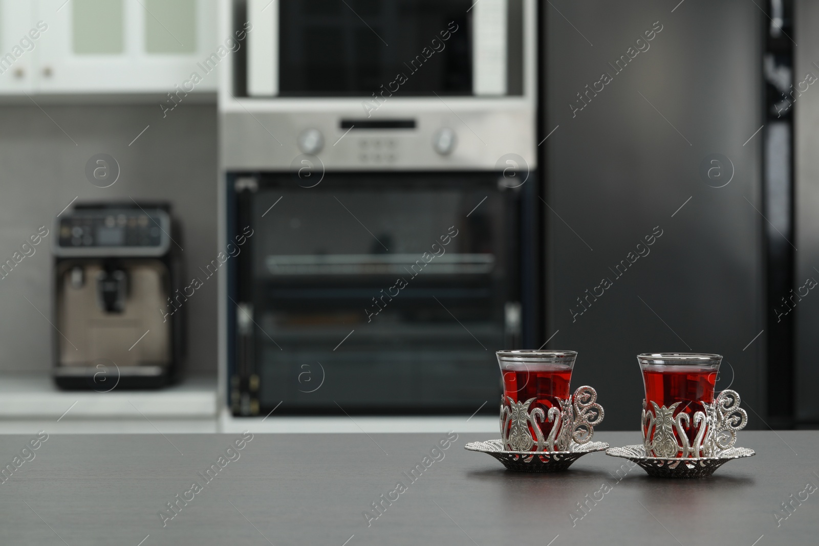 Photo of Glasses of delicious tea in vintage holders on grey table. Space for text