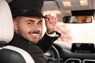 Photo of Young handsome driver in luxury car. Chauffeur service