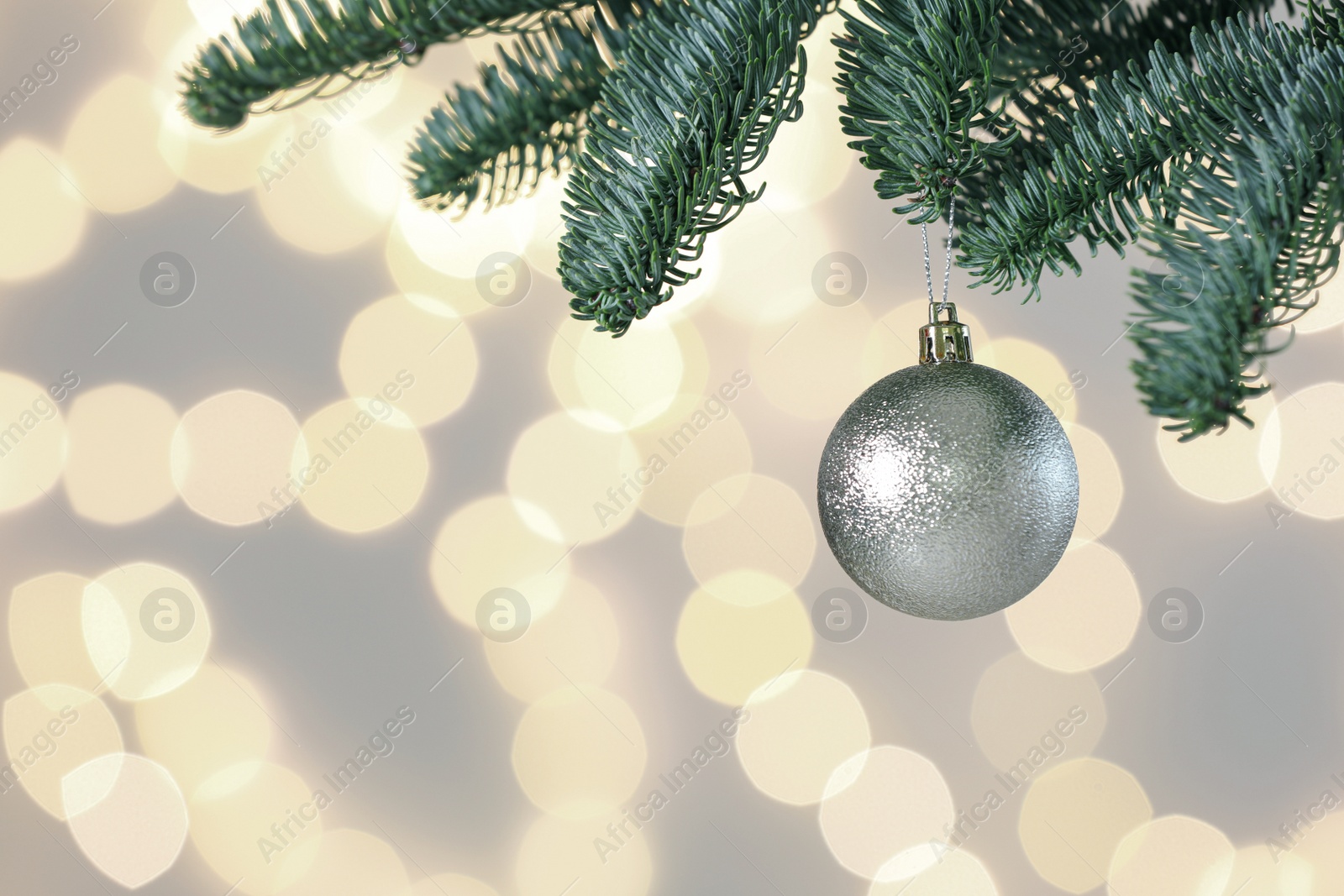 Photo of Beautiful holiday bauble hanging on Christmas tree against blurred lights, closeup. Space for text