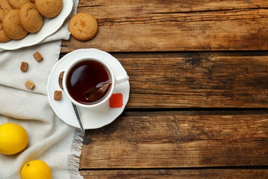 Photo of Flat lay composition with tea bag in cup of hot water on wooden table, space for text