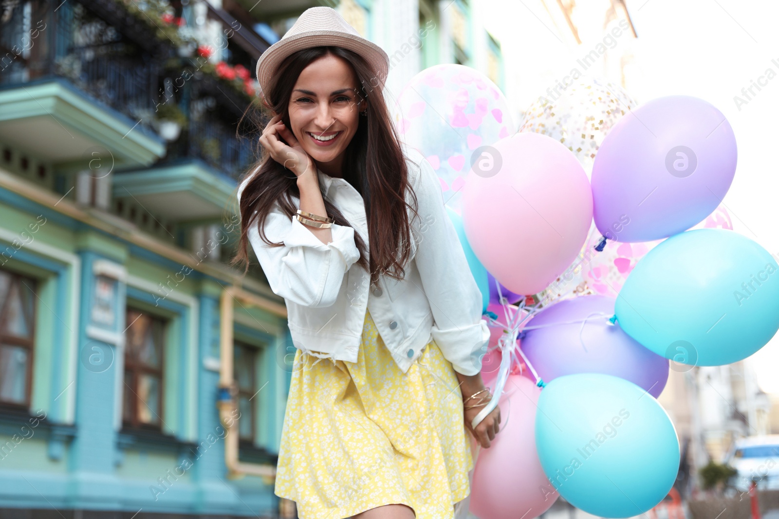 Photo of Beautiful young woman with color balloons on city street