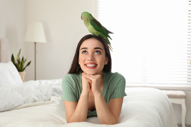 Young woman with Alexandrine parakeet indoors. Cute pet