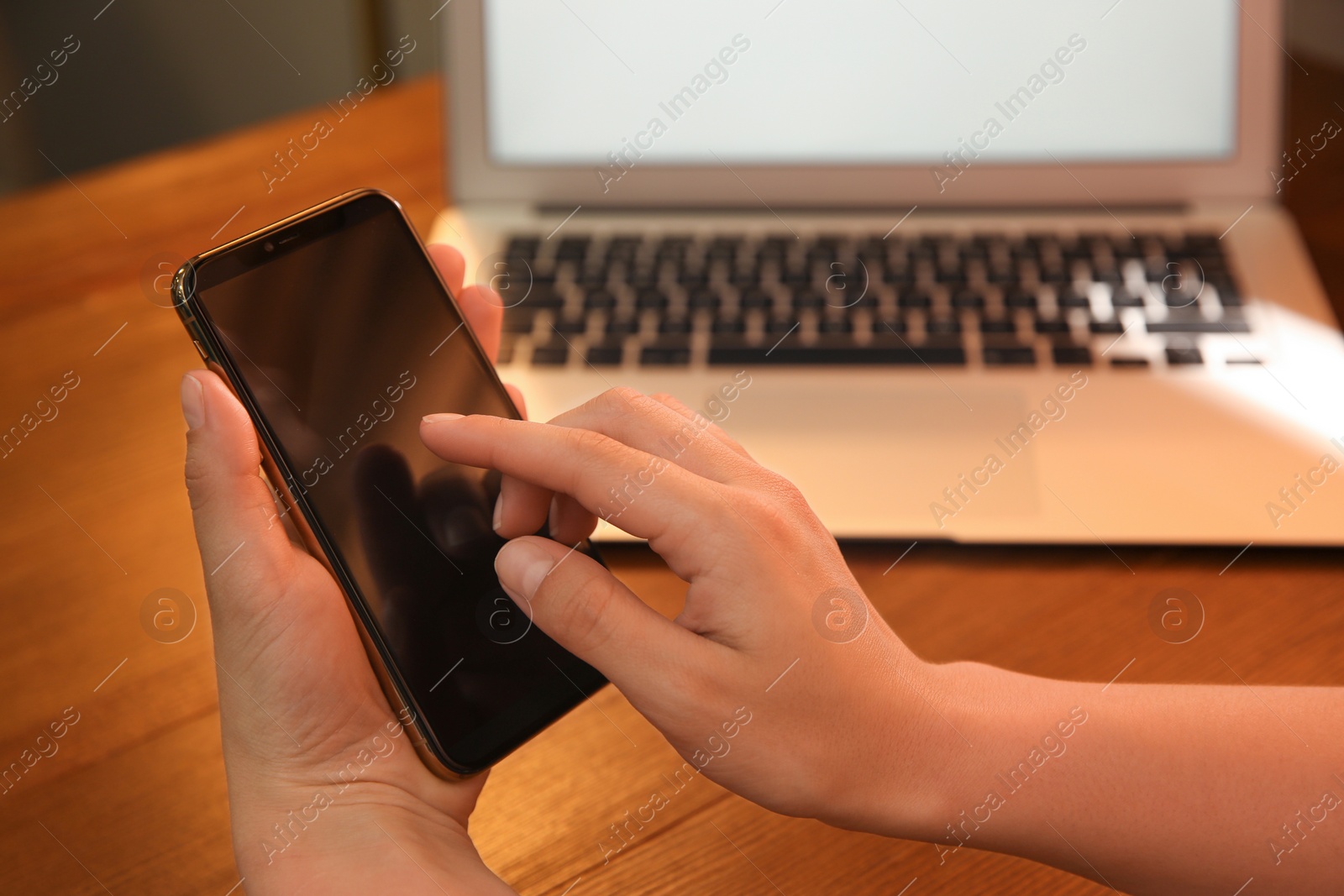 Photo of Woman with modern smartphone at wooden table, closeup