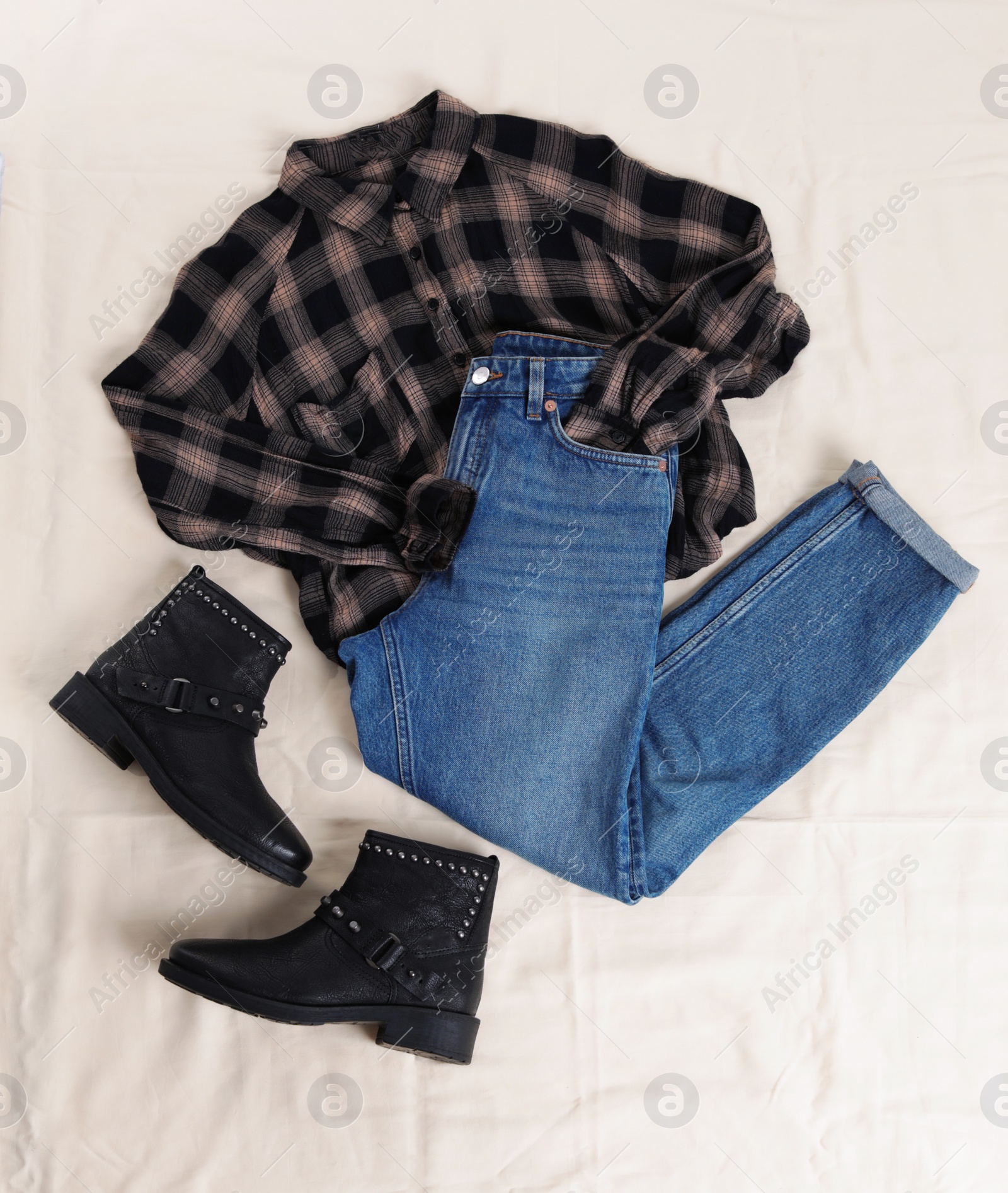 Photo of Flat lay composition with jeans, flannel shirt and shoes on white fabric