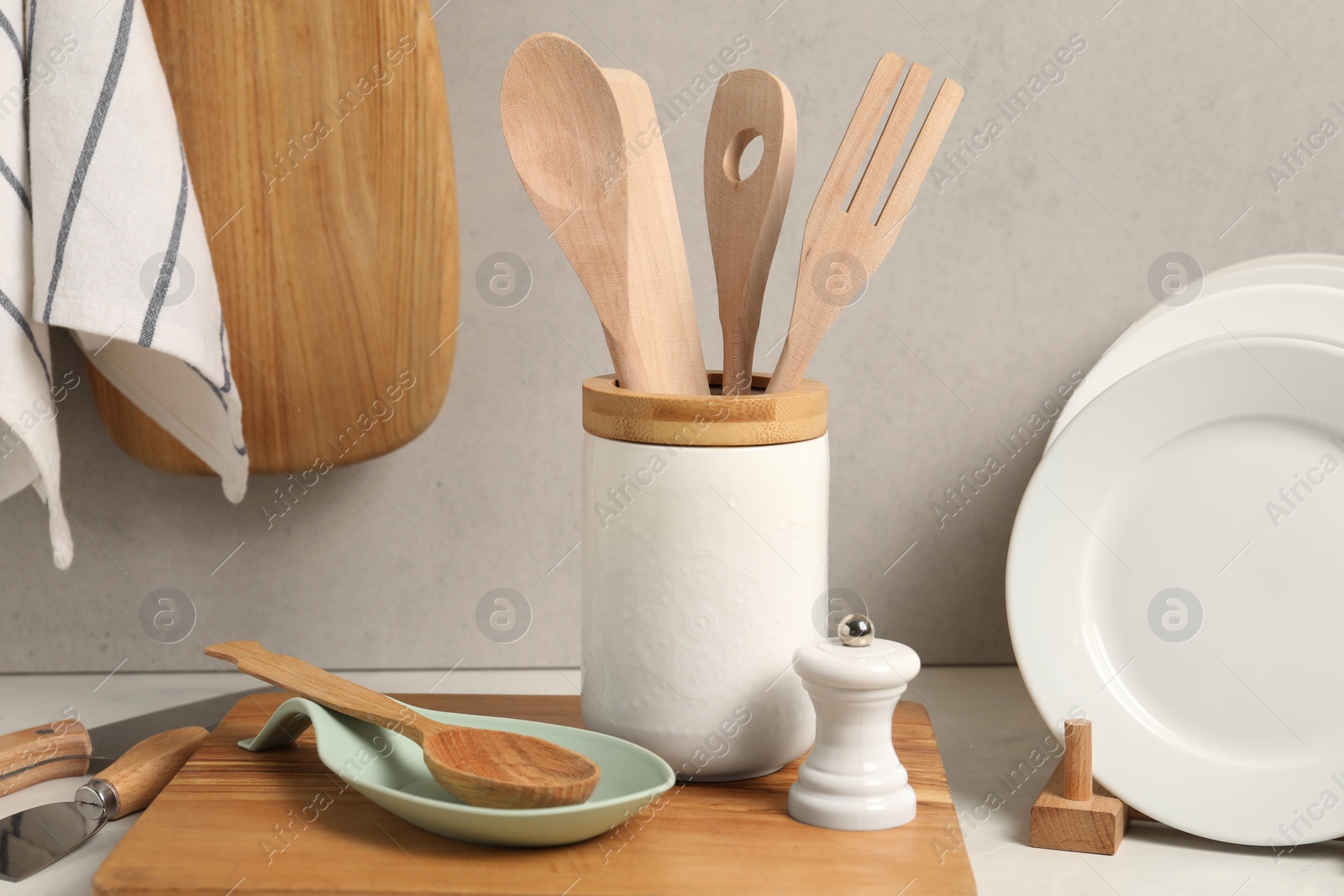 Photo of Set of different kitchen utensils and plates on white near gray wall