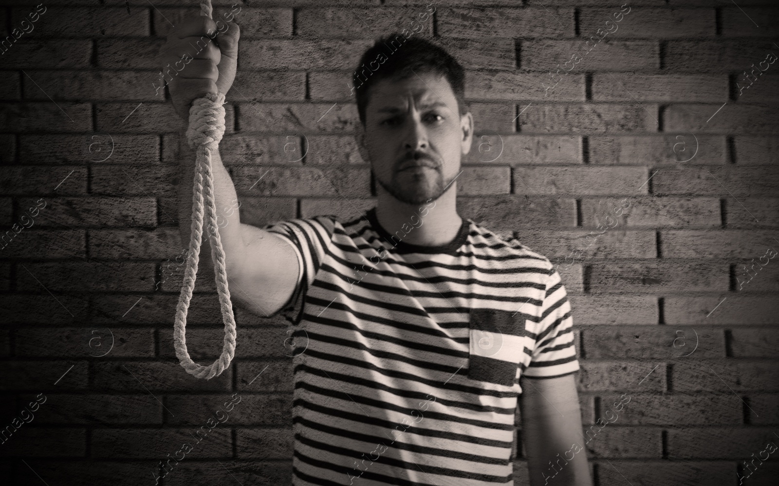 Image of Depressed man with rope noose near brick wall. Suicide concept