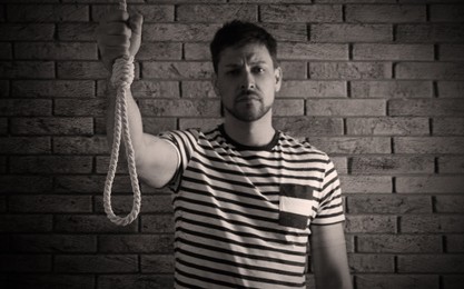 Image of Depressed man with rope noose near brick wall. Suicide concept