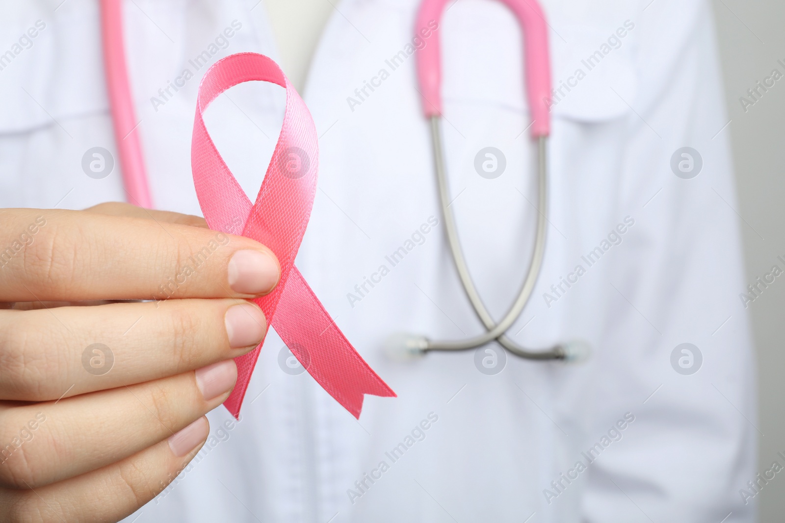 Photo of Doctor holding pink ribbon, closeup. Breast cancer awareness