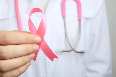 Doctor holding pink ribbon, closeup. Breast cancer awareness