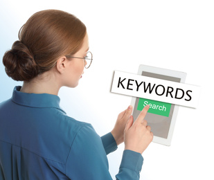 Woman with tablet searching for keywords on white background