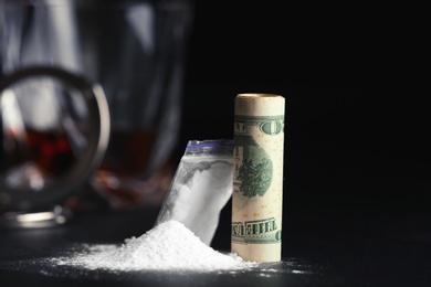 Photo of Cocaine and rolled money bill on dark table, closeup