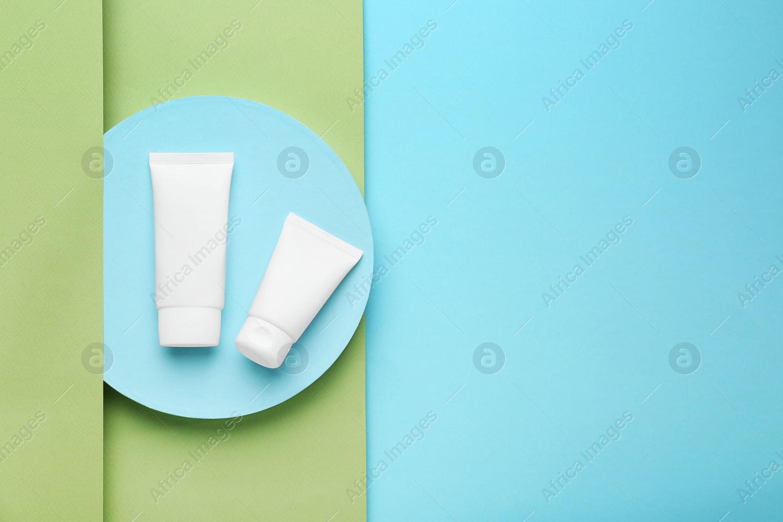 Photo of Tubes of hand cream on turquoise background, flat lay. Space for text