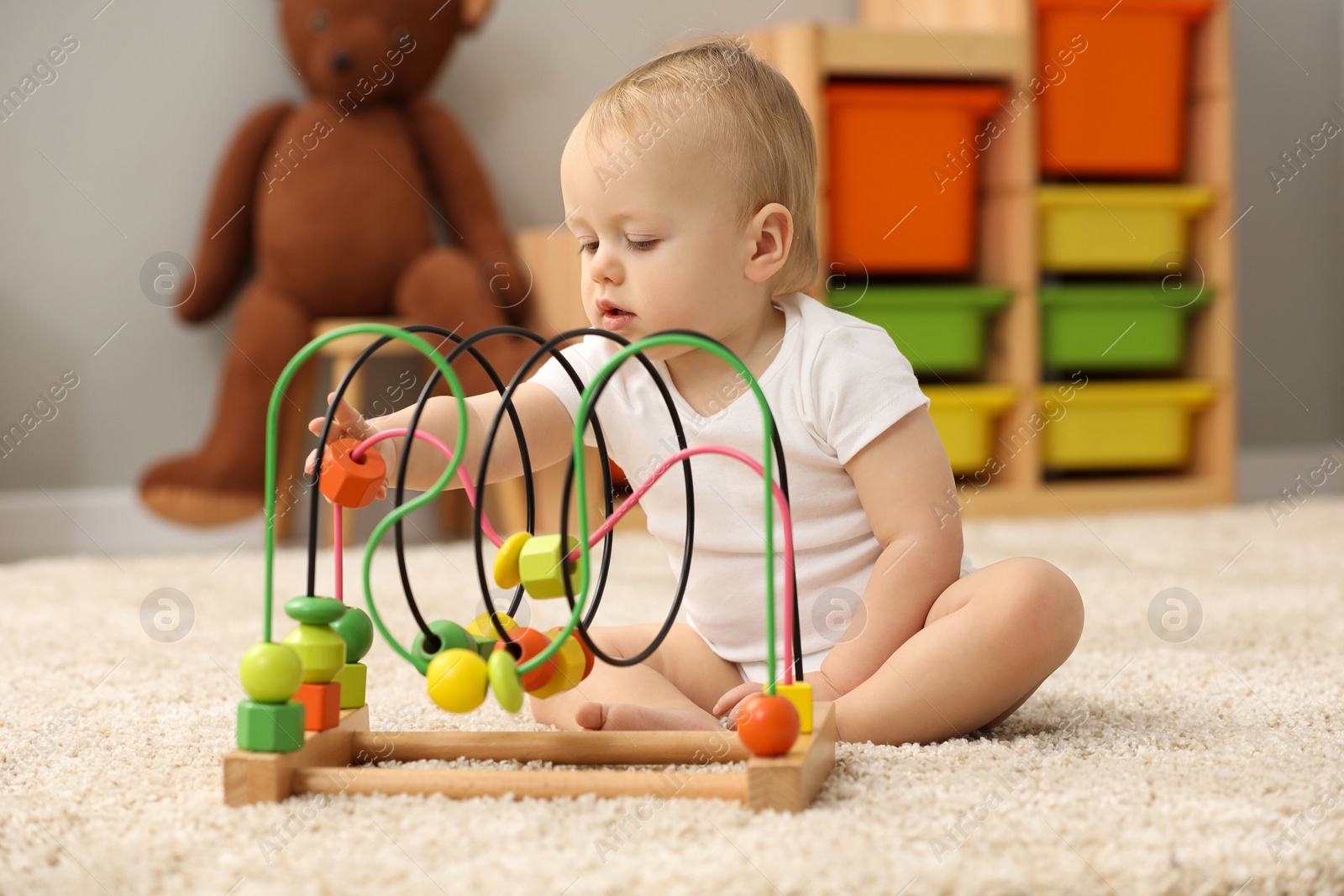 Photo of Children toys. Cute little boy playing with bead maze on rug at home