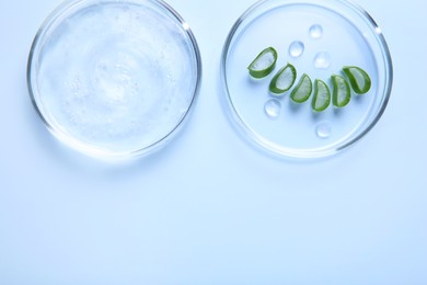 Cut aloe vera and cosmetic gel on light blue background, top view. Space for text