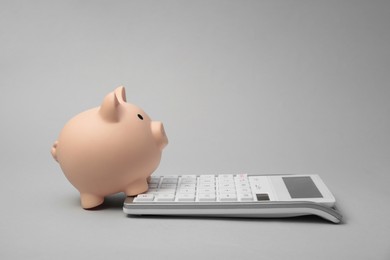 Calculator and piggy bank on grey background