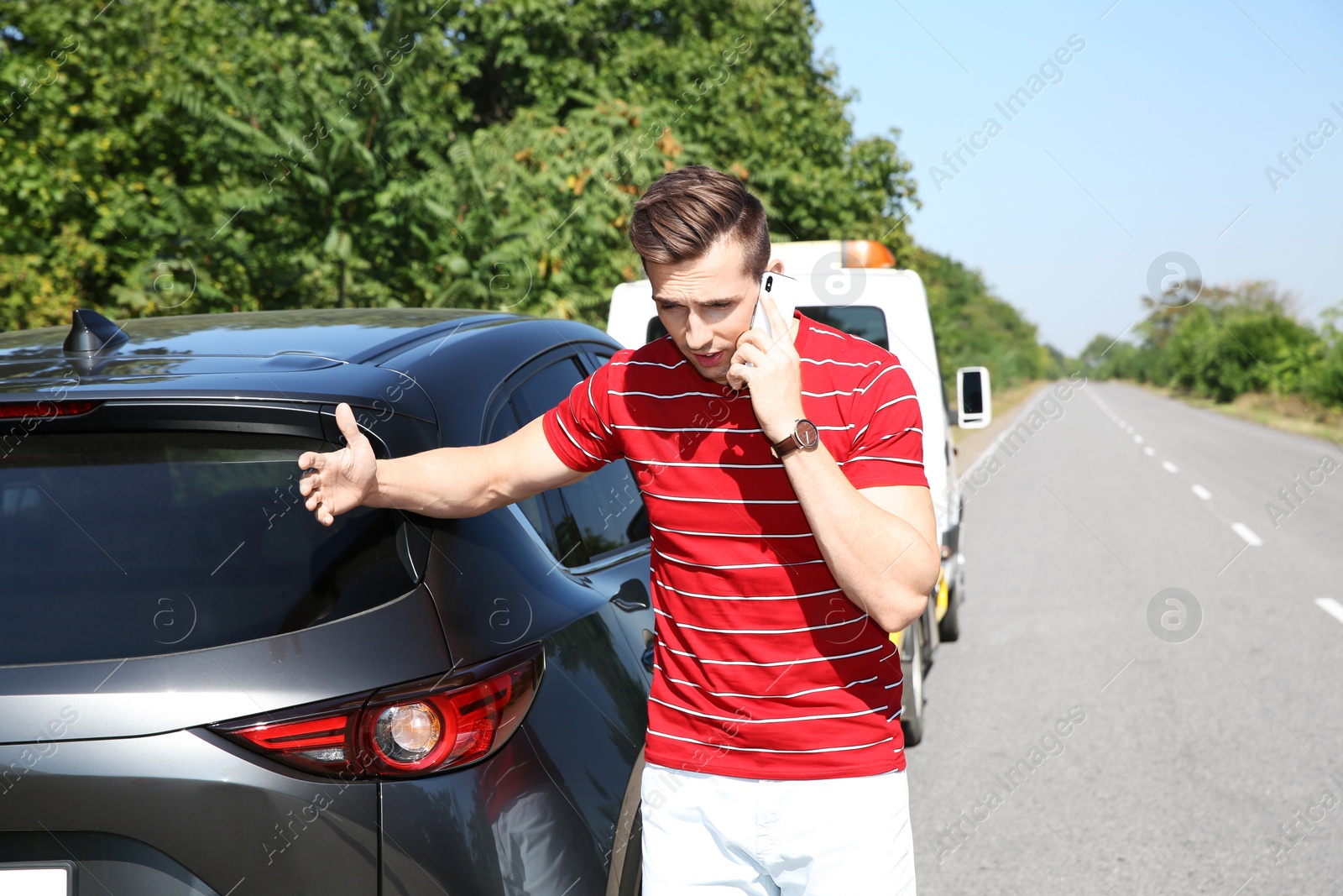 Photo of Man talking on phone near broken car outdoors