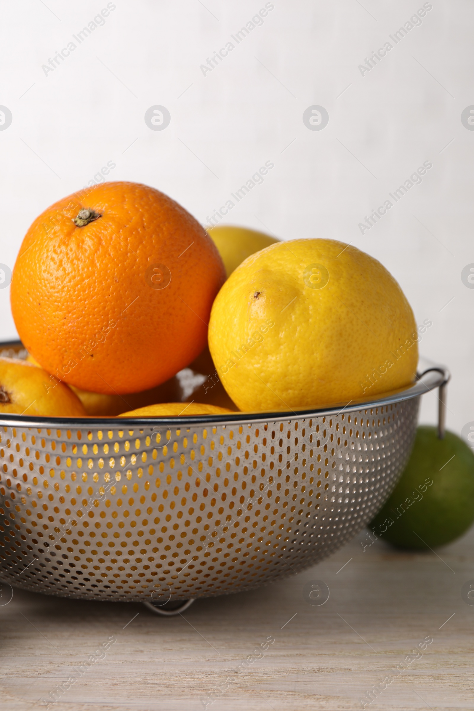 Photo of Different fresh fruits in colander on white wooden table, closeup