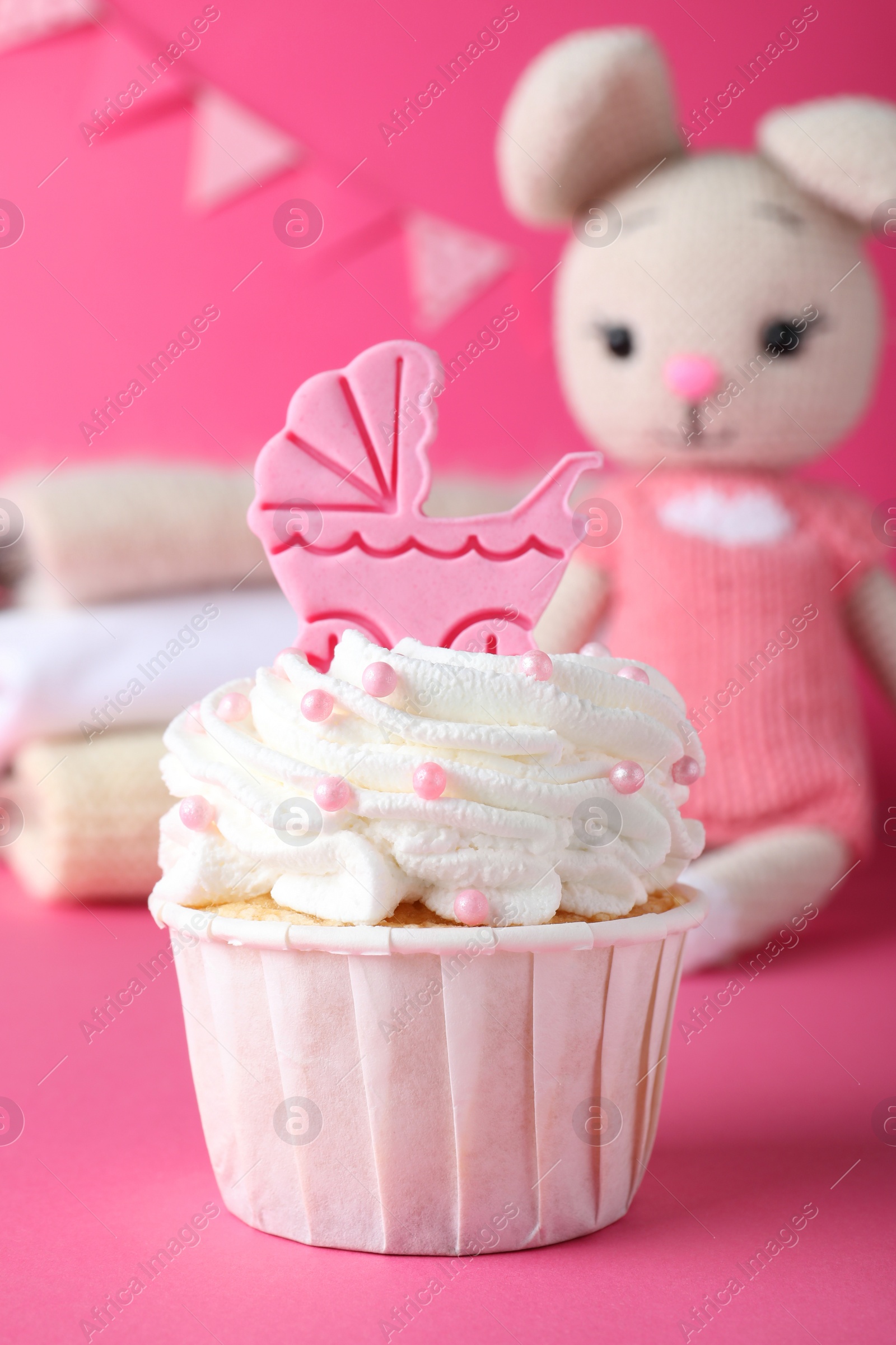 Photo of Beautifully decorated baby shower cupcake for girl with cream and topper on pink background