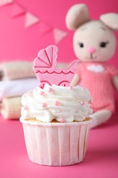 Beautifully decorated baby shower cupcake for girl with cream and topper on pink background