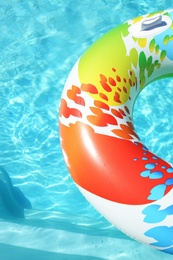 Photo of Colorful inflatable ring floating in swimming pool on sunny day. Space for text