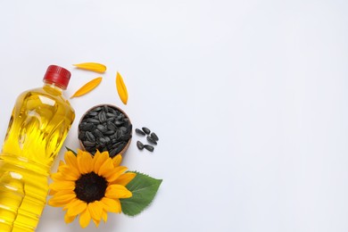 Bottle of cooking oil, sunflower and seeds on white table, flat lay. Space for text