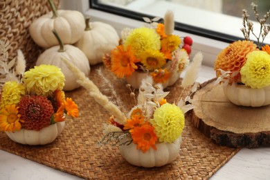 Composition with small pumpkins, beautiful flowers and spikelets on window sill indoors