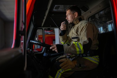 Photo of Firefighter using portable radio set while driving fire truck