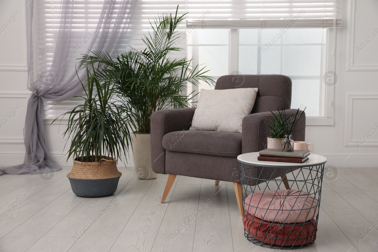 Photo of Comfortable place for rest with grey armchair near window indoors