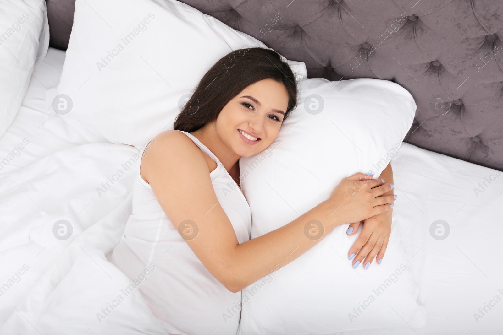 Photo of Beautiful pregnant woman lying on comfortable pillow in bed at home, top view