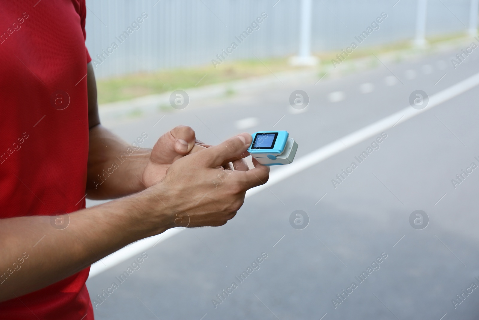 Photo of Young man checking pulse with medical device after training, closeup