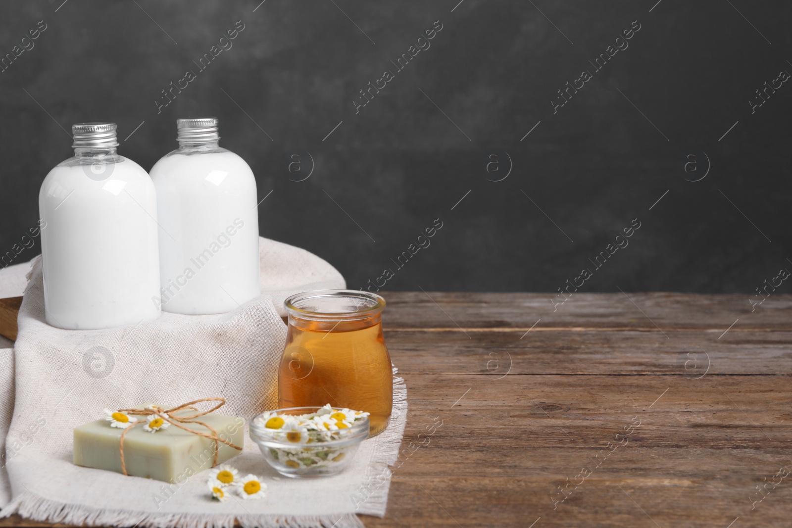 Photo of Composition with chamomile flowers and cosmetic products on wooden table, space for text