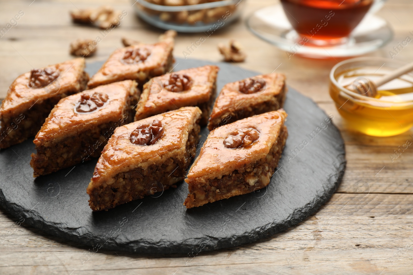 Photo of Delicious honey baklava with walnuts served on wooden table, closeup