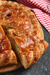 Photo of Cut delicious homemade pie on black table, closeup