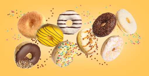 Sweet tasty donuts with sprinkles flying on yellow background