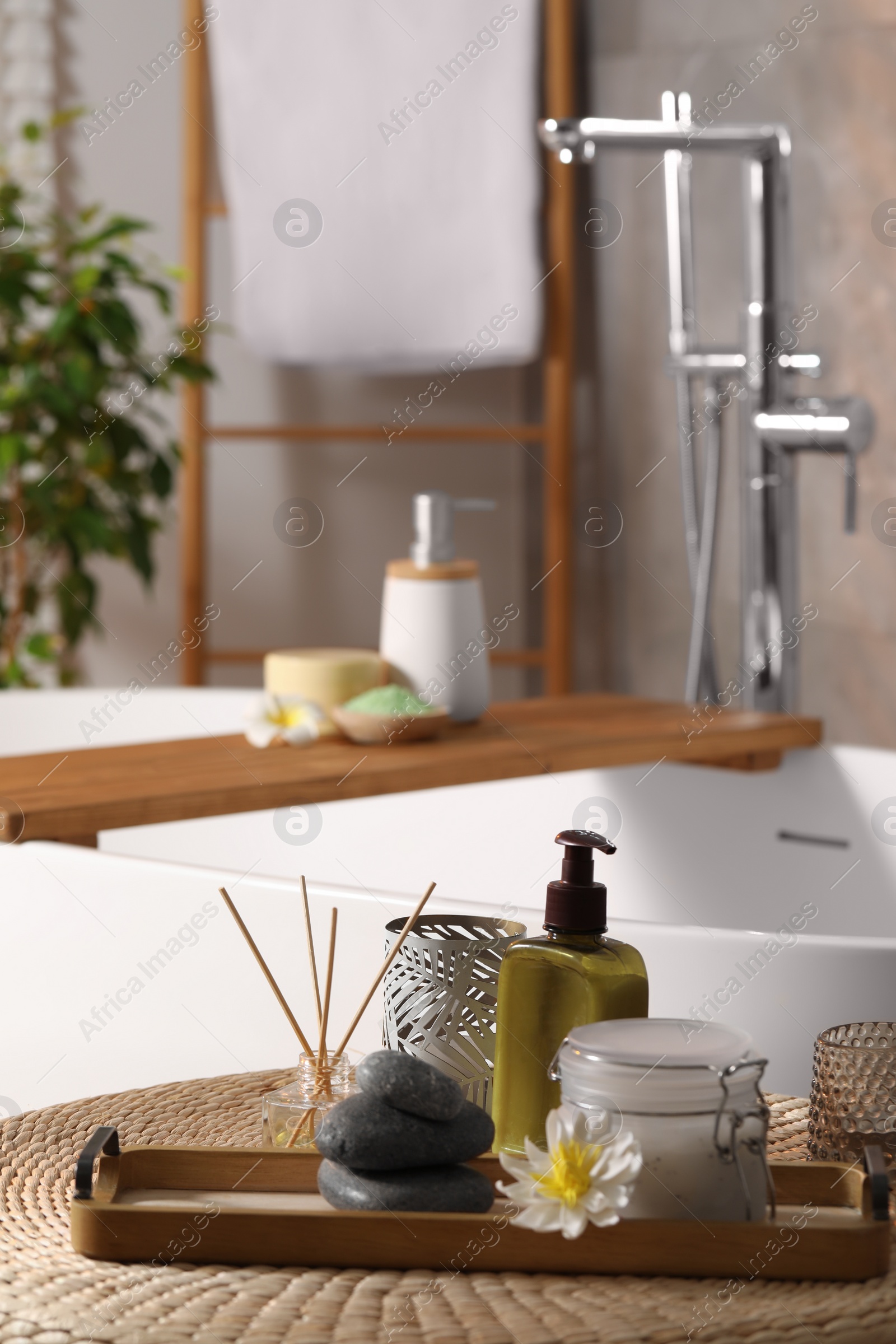 Photo of Different spa products and beautiful flower on wicker table in bathroom. Space for text