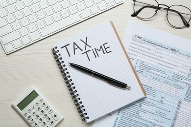 Photo of Notebook with words Tax Time, documents, keyboard and calculator on white wooden table, flat lay